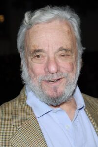 Stephen Sondheim, white-bearded and smiling, in a tweed jacket over a blue open-collar shirt