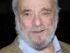 Stephen Sondheim, white-bearded and smiling, in a tweed jacket over a blue open-collar shirt